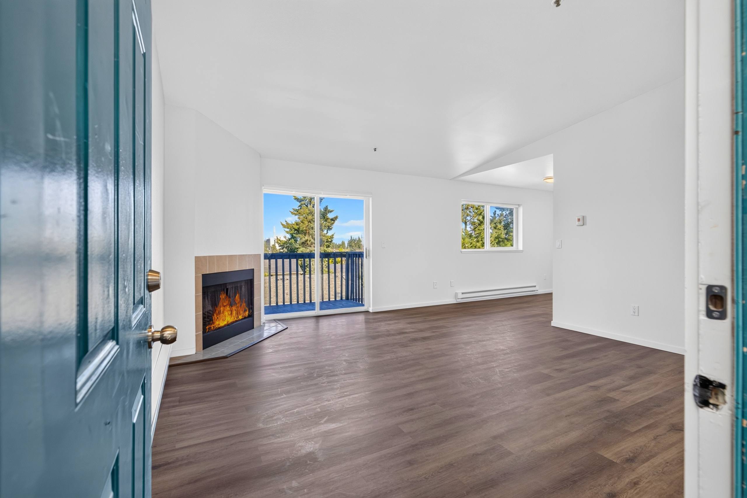 A room with a fireplace and a view of trees outside the window.