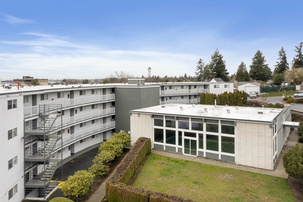a view of the roof of a building with a lawn and trees