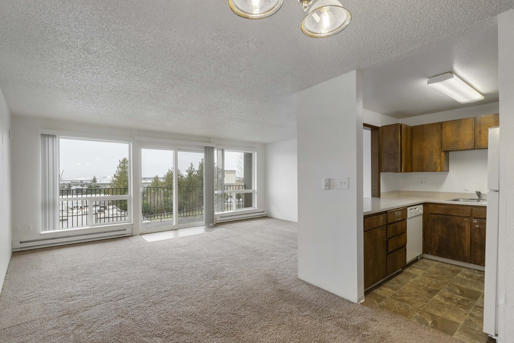 an empty living room with a balcony and a kitchen