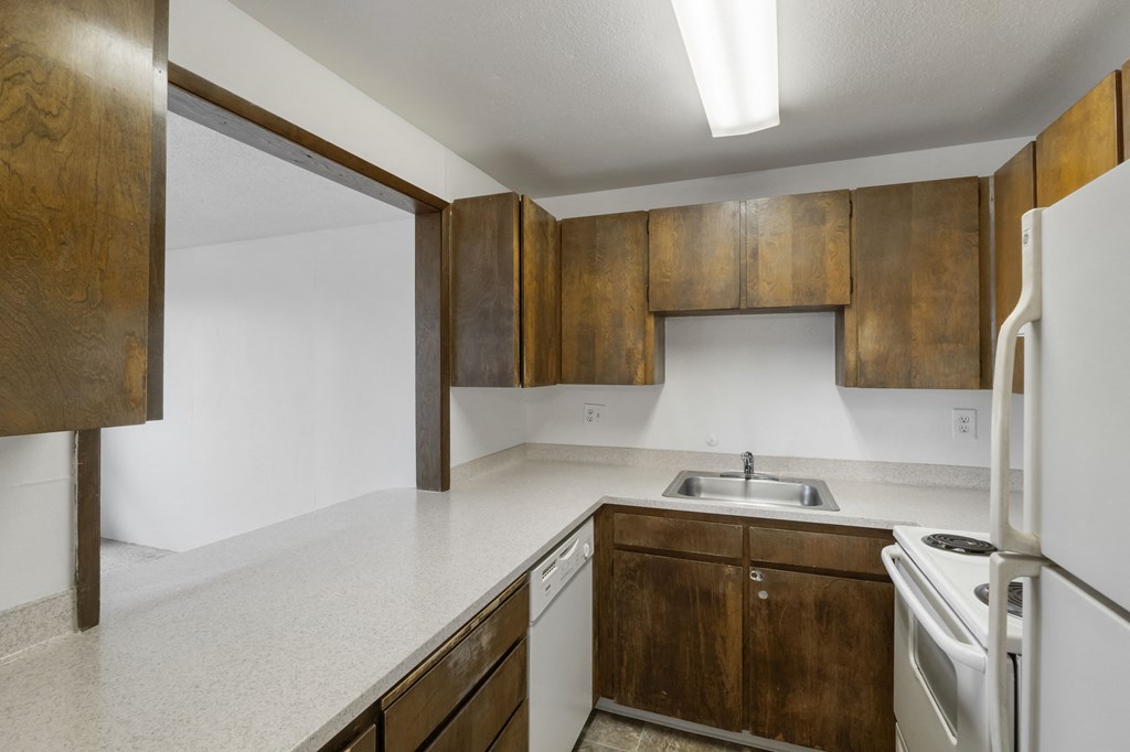 an empty kitchen with white appliances and wooden cabinets