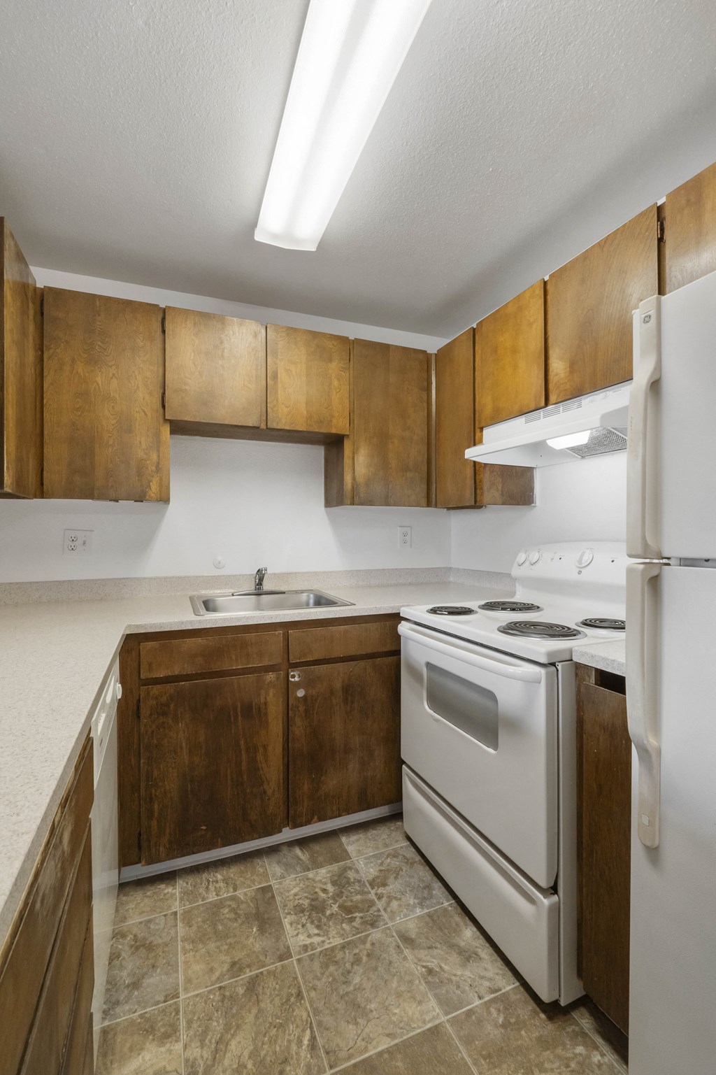 an empty kitchen with white appliances and wooden cabinets