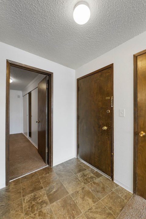 an empty room with two doors and a hallway with a door to a closet