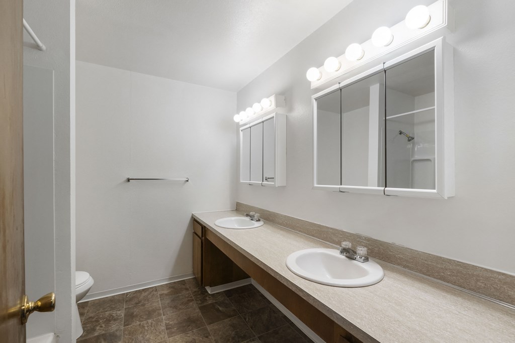 an empty bathroom with two sinks and a mirror
