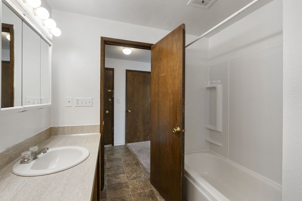 a bathroom with a white sink and a shower and a wooden door