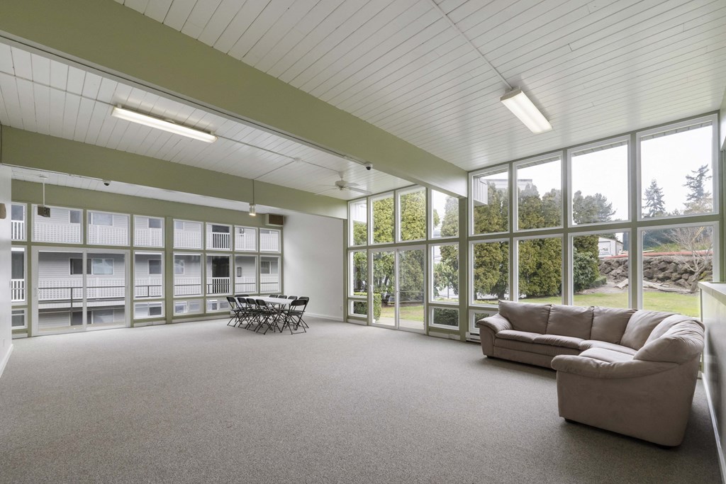 a living room with a couch and a table in front of large windows