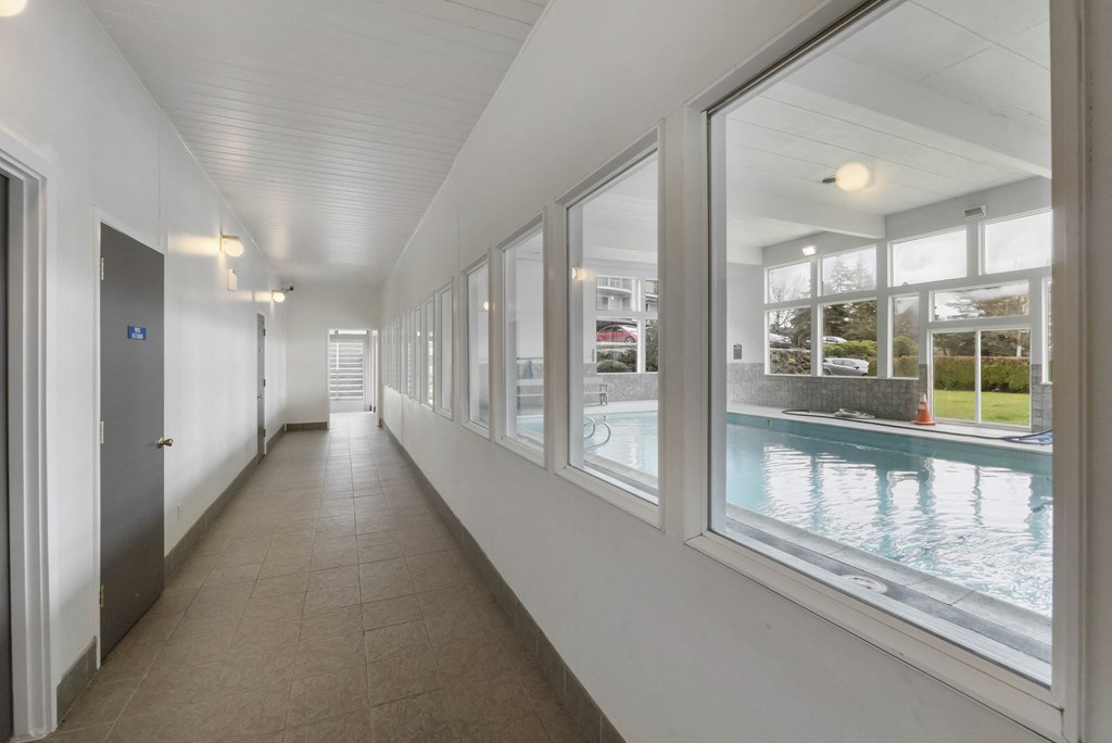 a long hallway with large windows next to a swimming pool