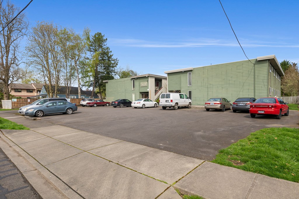 A parking lot with cars and a green building in the background.