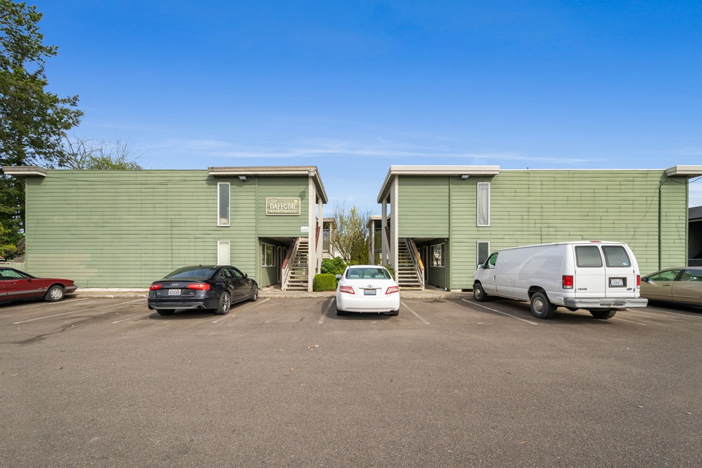 A parking lot with cars and two green buildings with the word "Bank" on them.