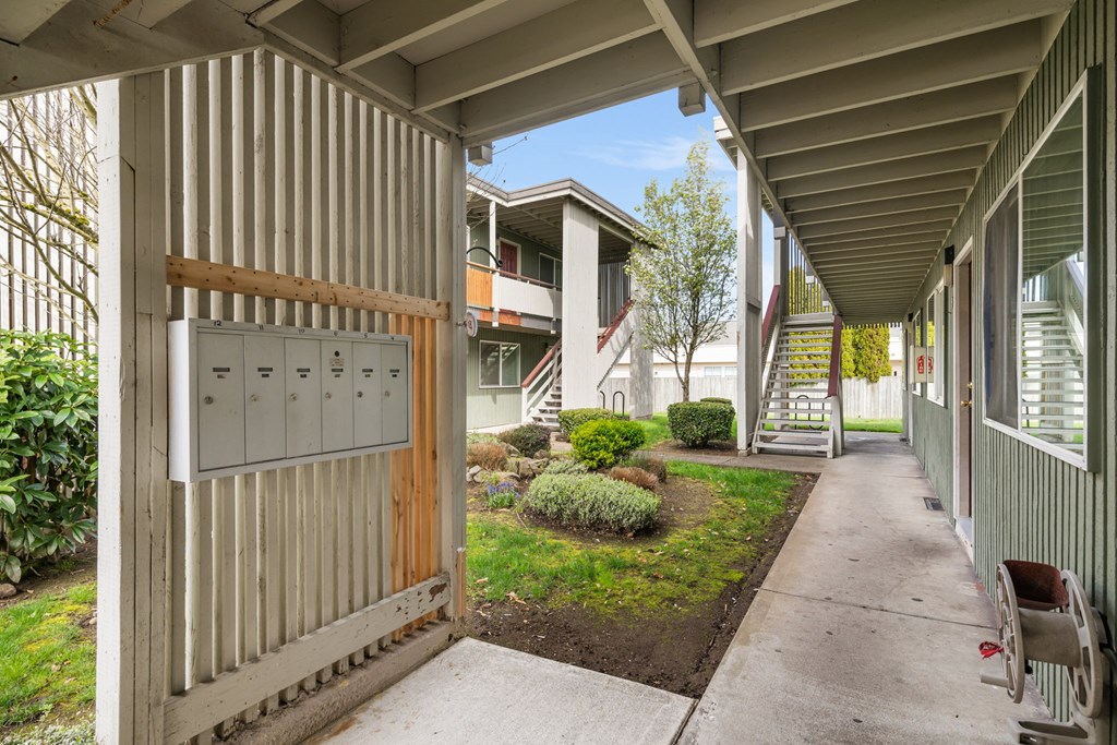 A corridor with a wooden gate and a metal mailbox.