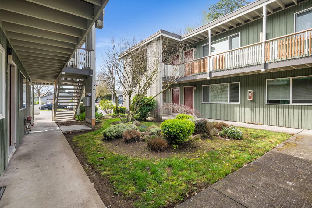 A concrete walkway leads to a building with a balcony.