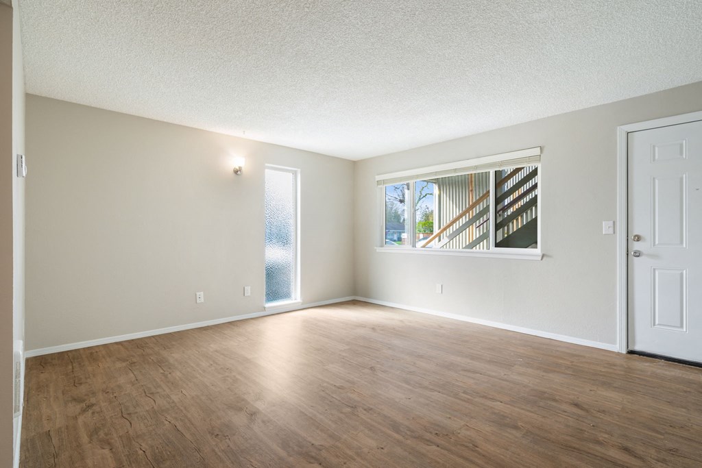 A room with wooden floors and a window showing a staircase outside.