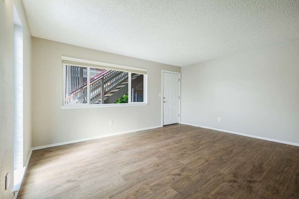 Empty room with wooden flooring and a window.