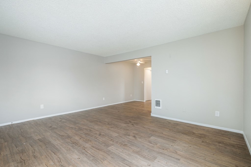 Empty room with wooden flooring and white walls.