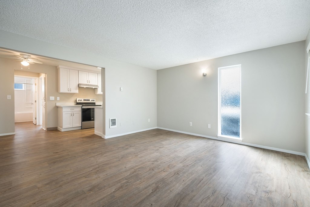 A large empty room with wooden floors and a window.