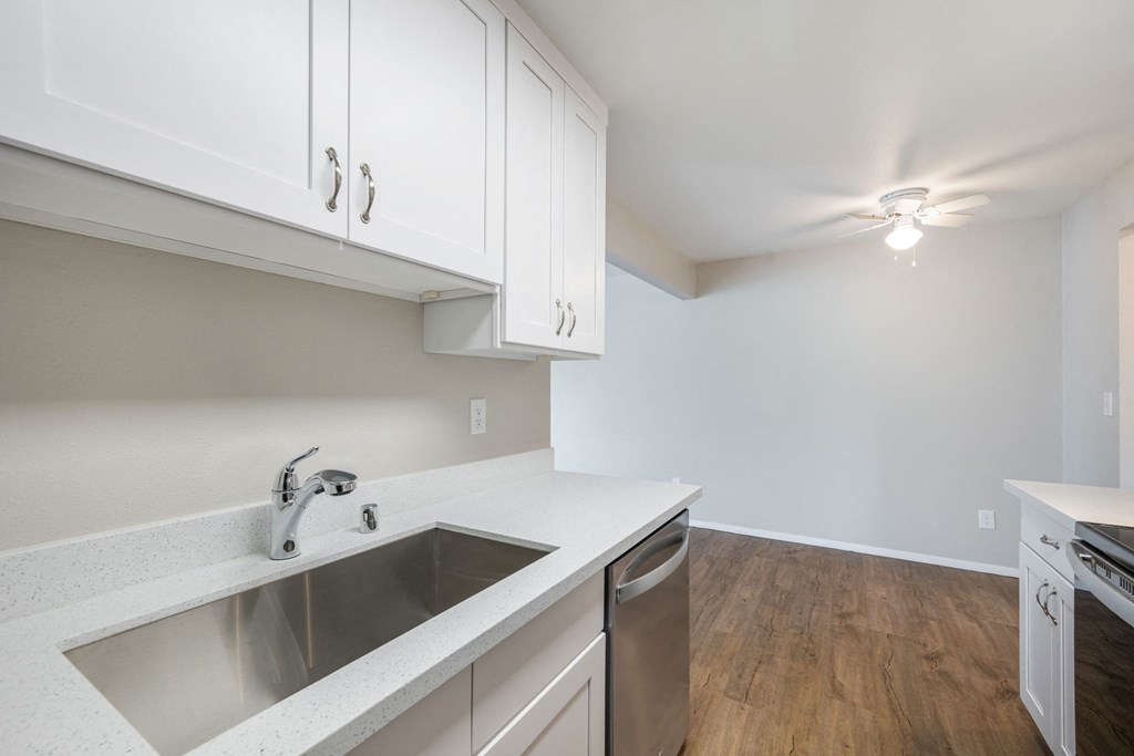 A kitchen with white cabinets and a stainless steel sink.