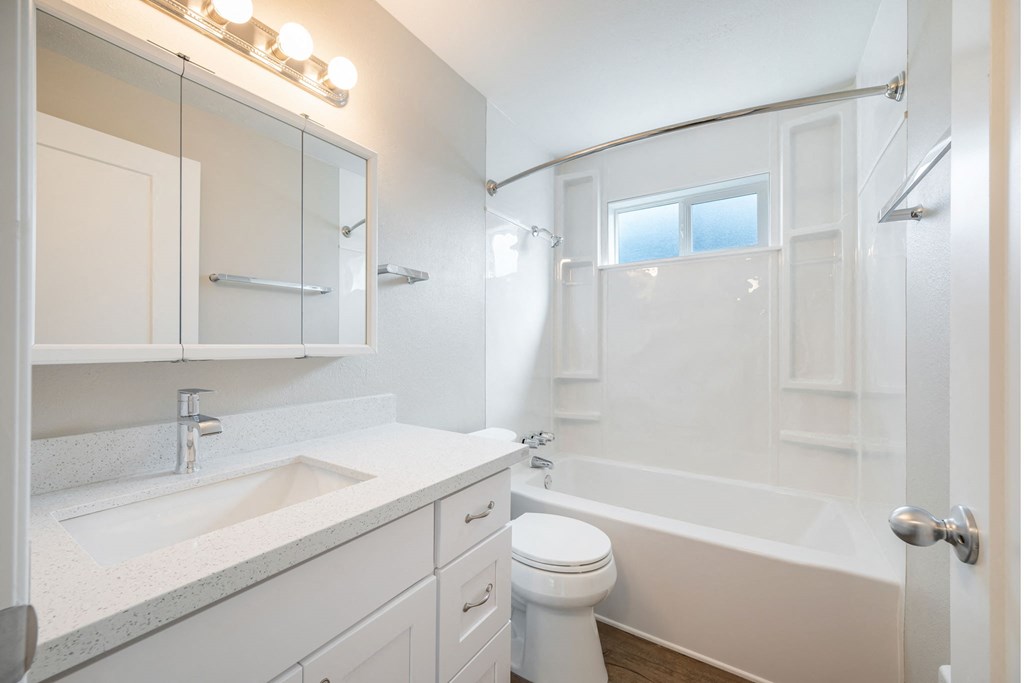 A white bathroom with a toilet, sink, and bathtub.