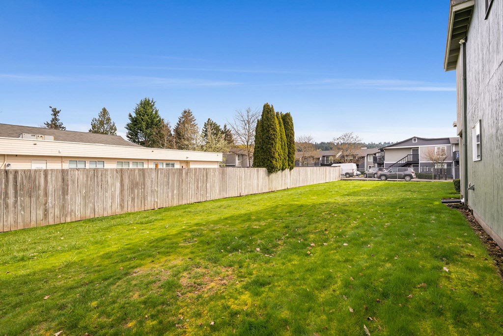 A backyard with a fence and a green lawn.