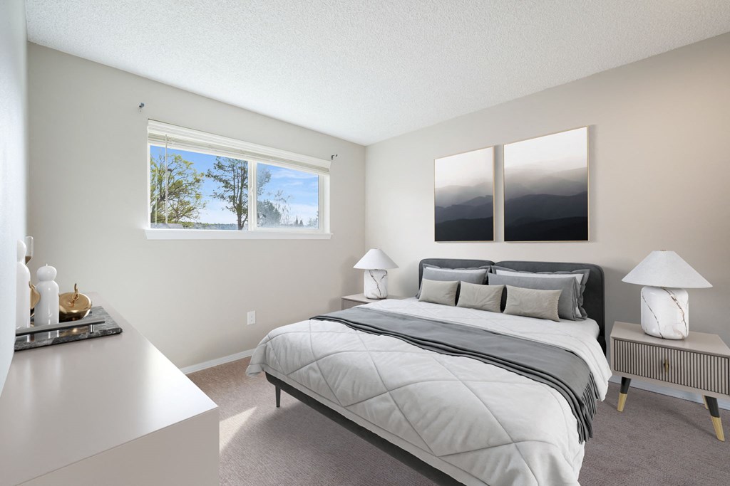 A bedroom with a large bed and a window overlooking a body of water.
