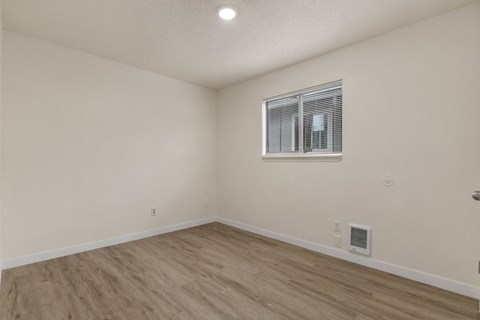 the living room of an apartment with wood flooring and a window