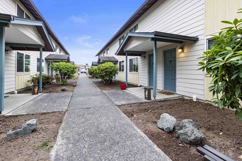a walkway in front of a building with plants and rocks