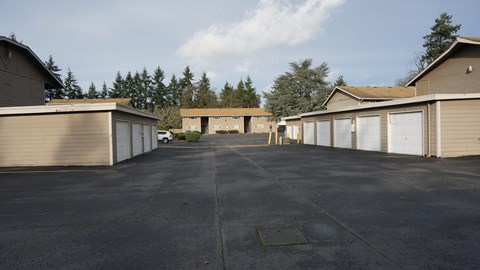 A parking lot with a few cars and a building in the background.