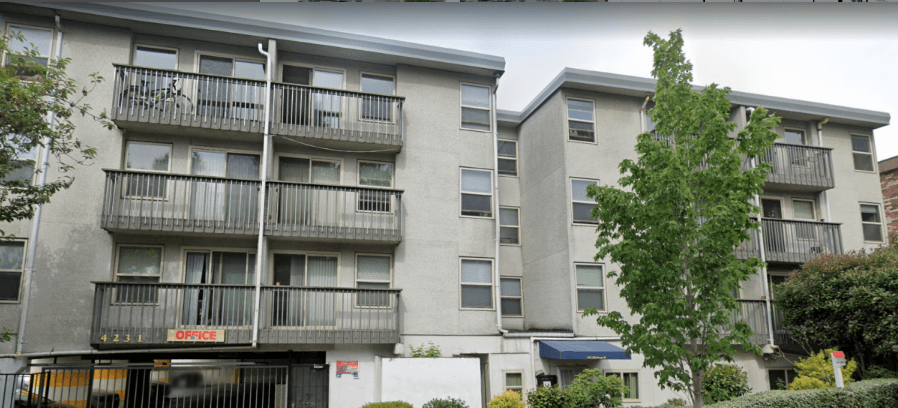 Apartment building with a tree in front.
