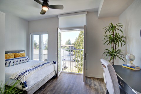 Bedroom with balcony door and desk workspace at The Hub Apartments, Washington