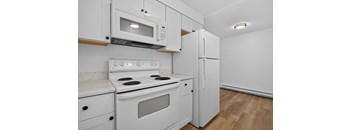 A white kitchen with a stove, microwave, and refrigerator.