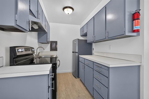 A kitchen with grey cabinets and a white counter.
