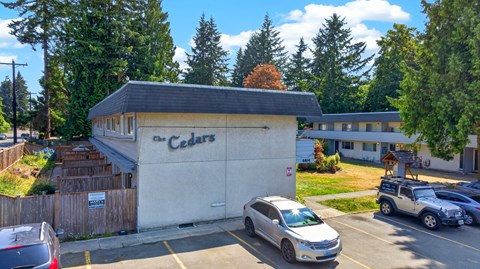 A grey car is parked in front of a building with a sign that says Cedars.