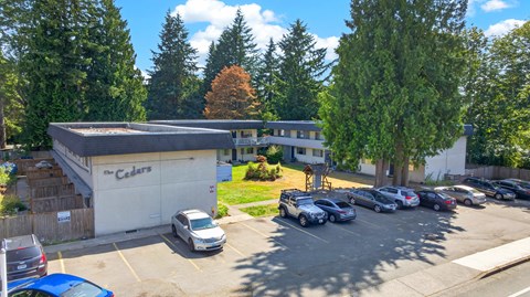 A parking lot with cars and a building with a sign that says "Cedars".