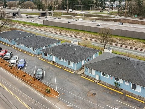 A parking lot with a few cars and a building with a yellow line in front of it.