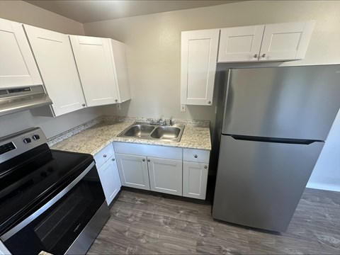 A kitchen with a stainless steel refrigerator, sink, and oven.