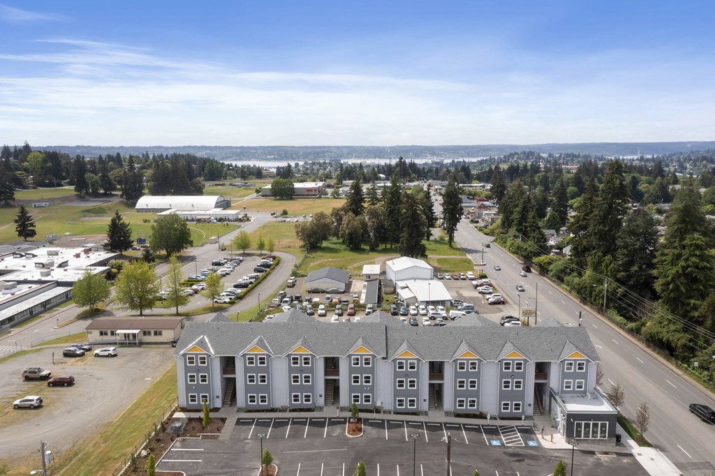 an aerial view of an apartment complex with a parking lot and trees
