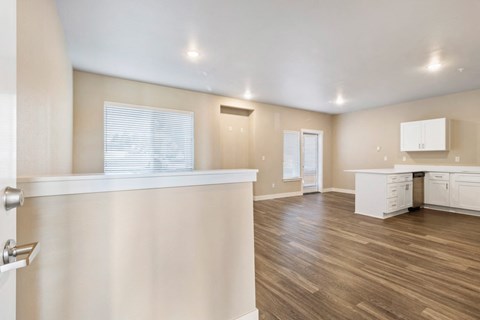 an empty kitchen and living room with white cabinets and wood flooring