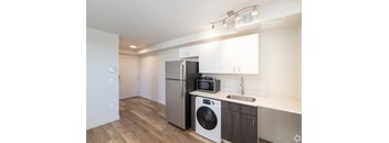 1-bedroom kitchen with modern stainless steel appliances and luxury vinyl wood plank flooring at Bode 125 Apartment homes in Seattle