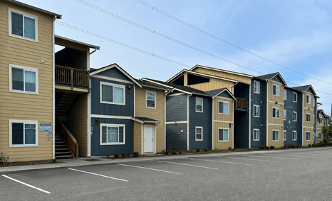 Apartment complex with a parking lot in front.