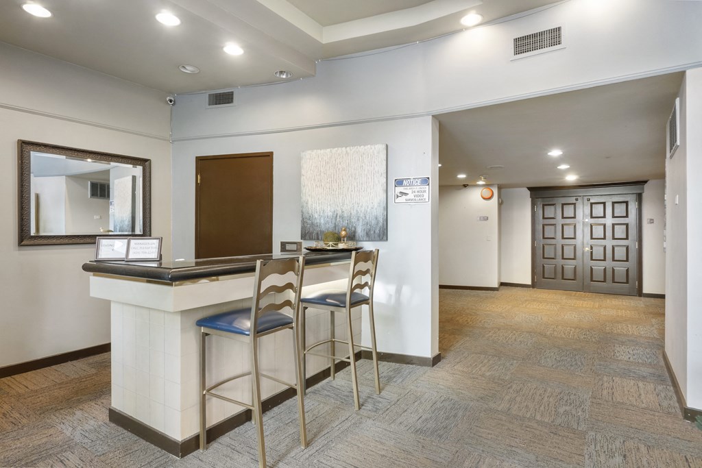 a lobby with a bar and two stools in front of a counter