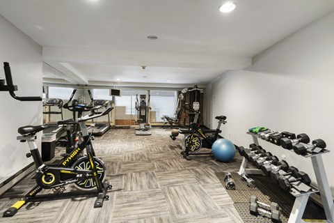 a gym with weights and bikes in the corner of a room