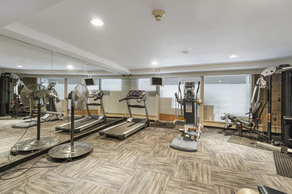 a gym with treadmills and other exercise equipment on a wooden floor