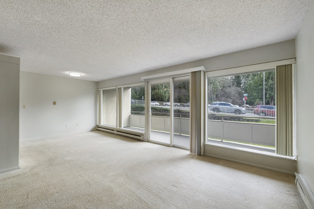 the living room of an empty apartment with large windows