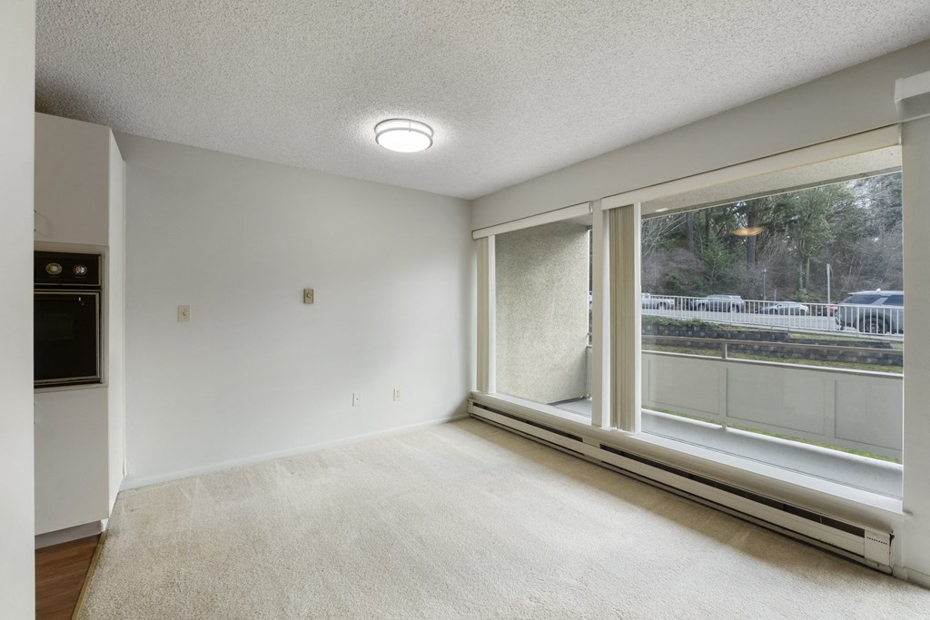 an empty living room with a large window and carpeting