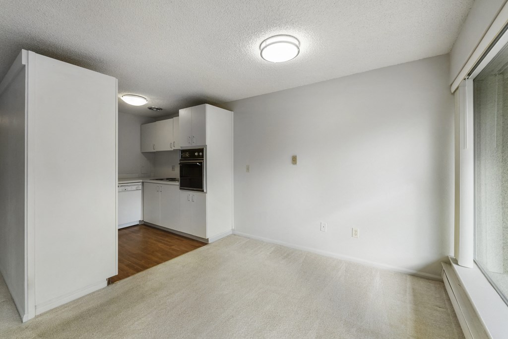 an empty living room and kitchen with white walls and wood floors