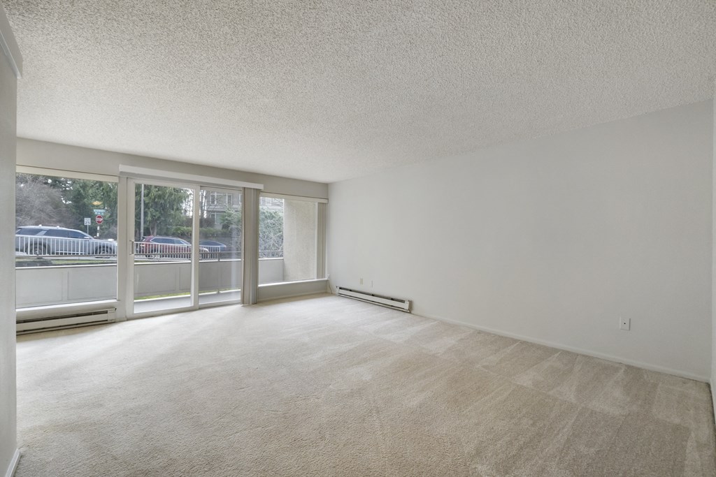 the living room of an apartment with a large window and white walls