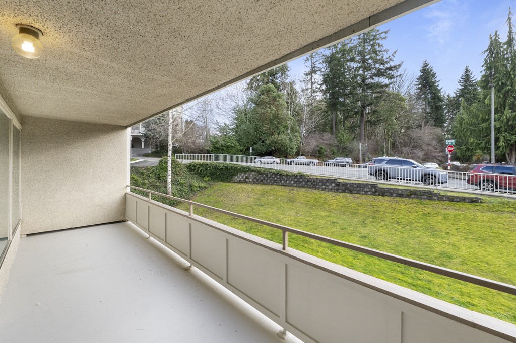 a balcony with a view of a parking lot and a grass field