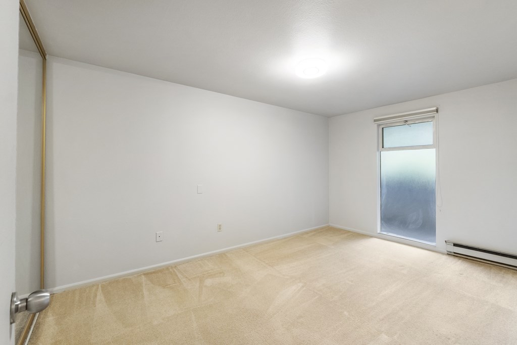 an empty room with a window and white walls