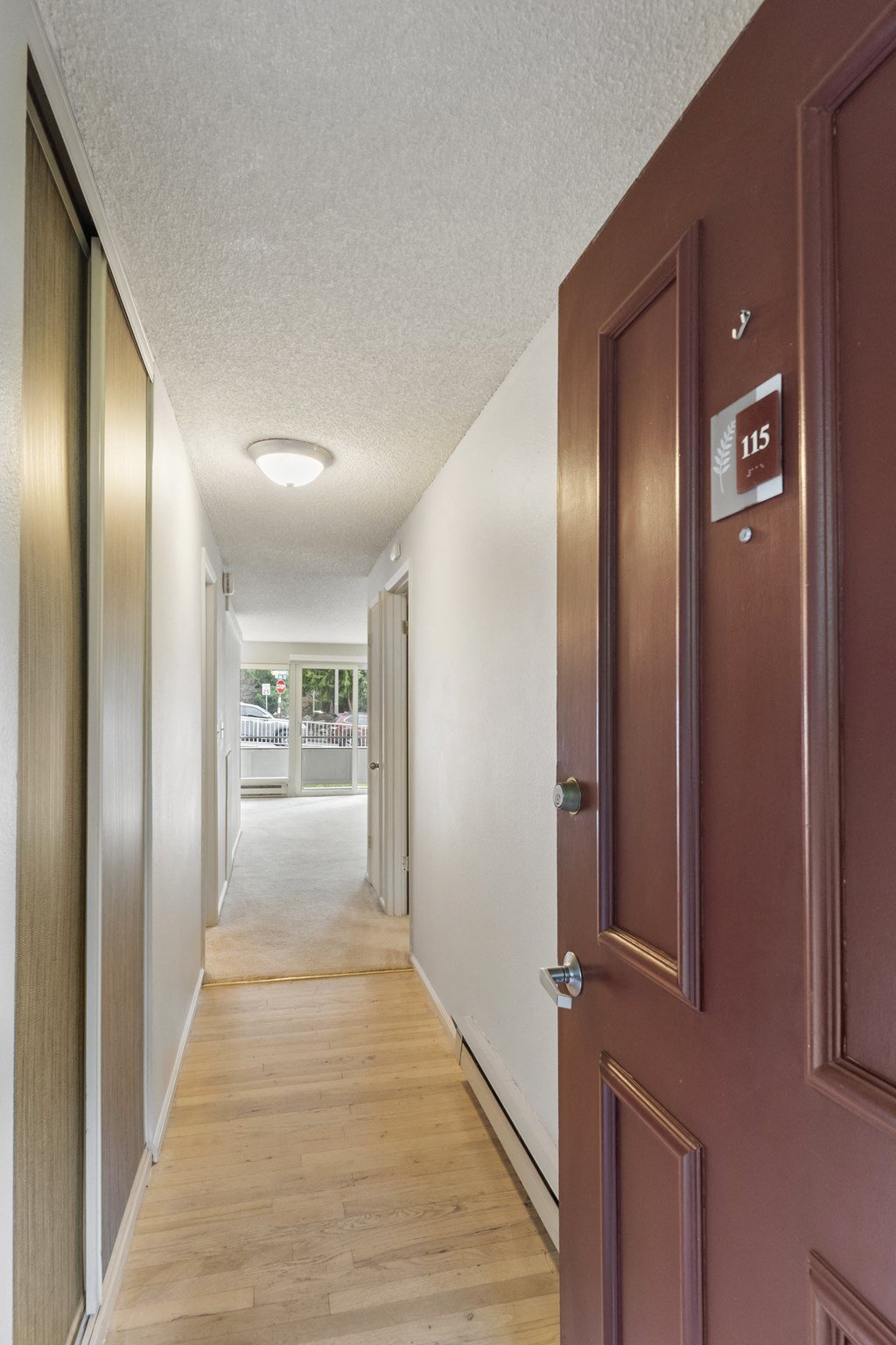a hallway with brown doors and white walls and a wood floor