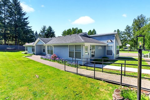 A house with a grey roof and a fence in front of it.