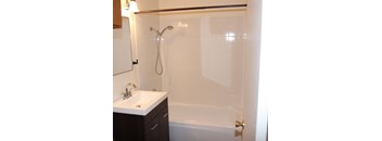 A white tiled bathroom with a sink and a bathtub.