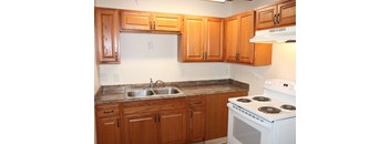 A kitchen with wooden cabinets and a white stove.